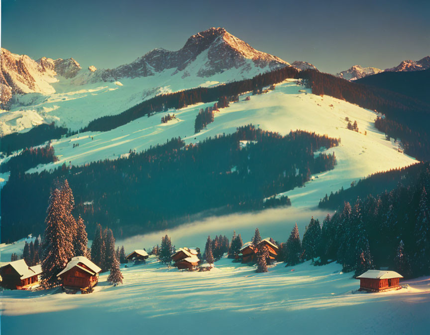 Snow-covered winter landscape with chalets, pine trees, and mountains at twilight