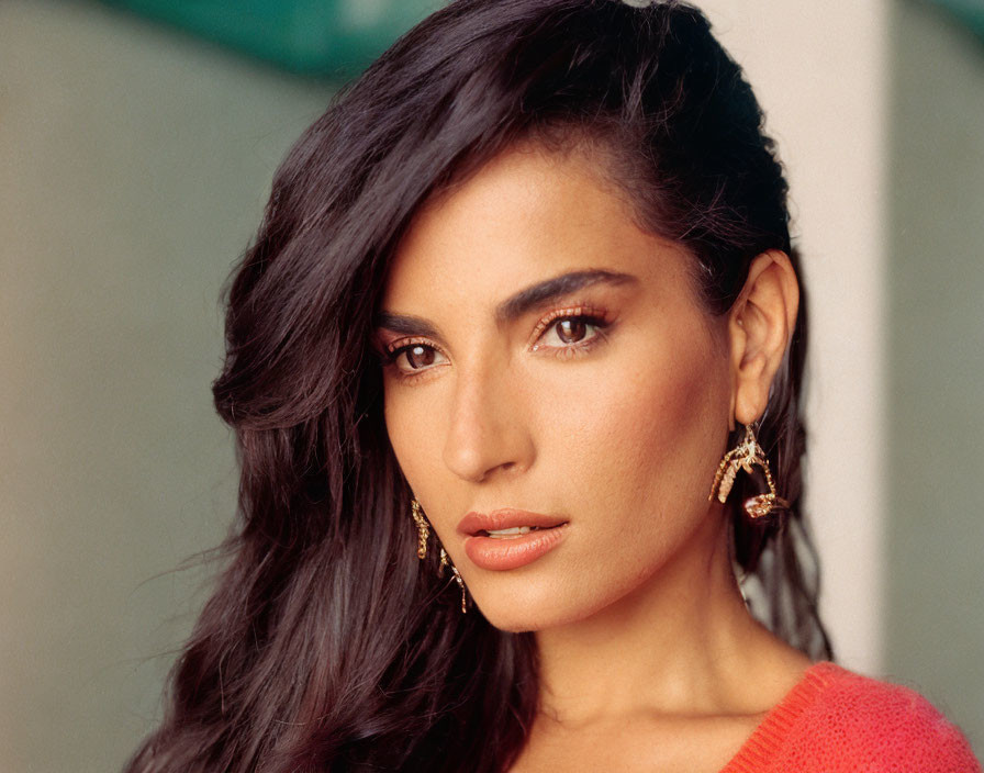 Portrait of woman with long dark hair and big earrings in red top