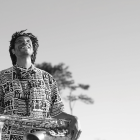 Man playing saxophone in surreal desert with floating spheres and fantastical rock formations