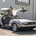 Futuristic DeLorean with open gull-wing doors and drone in dystopian cityscape