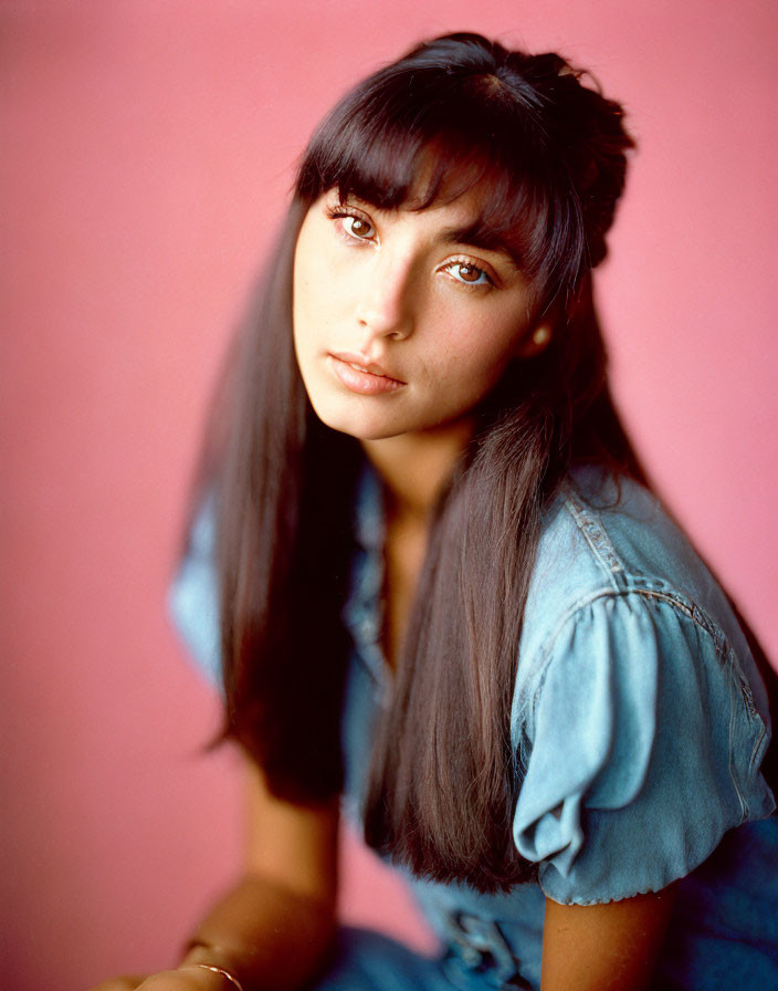 Dark-Haired Woman in Denim Outfit on Pink Background