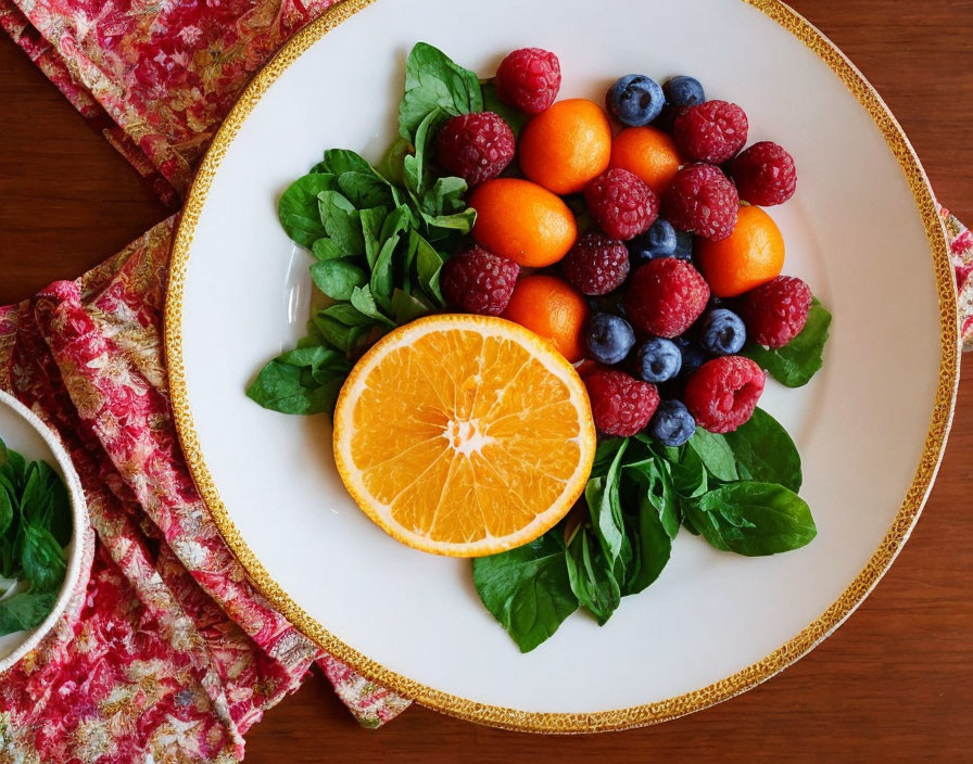 Vibrant fruit and spinach plate with berries, kumquats, and orange slice on wooden