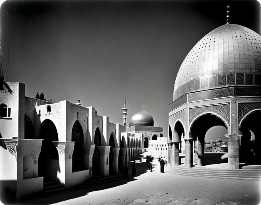 Monochrome image of ornate dome, traditional buildings, people under night sky