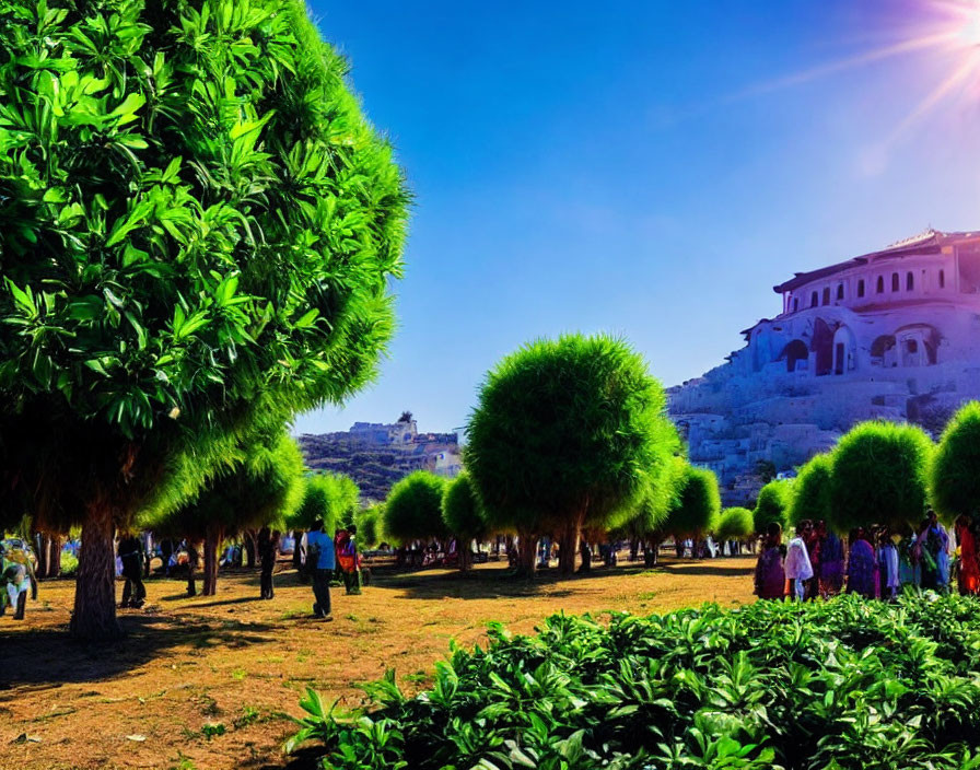 Scenic park with round-topped trees, people walking, historic buildings, and clear blue sky.