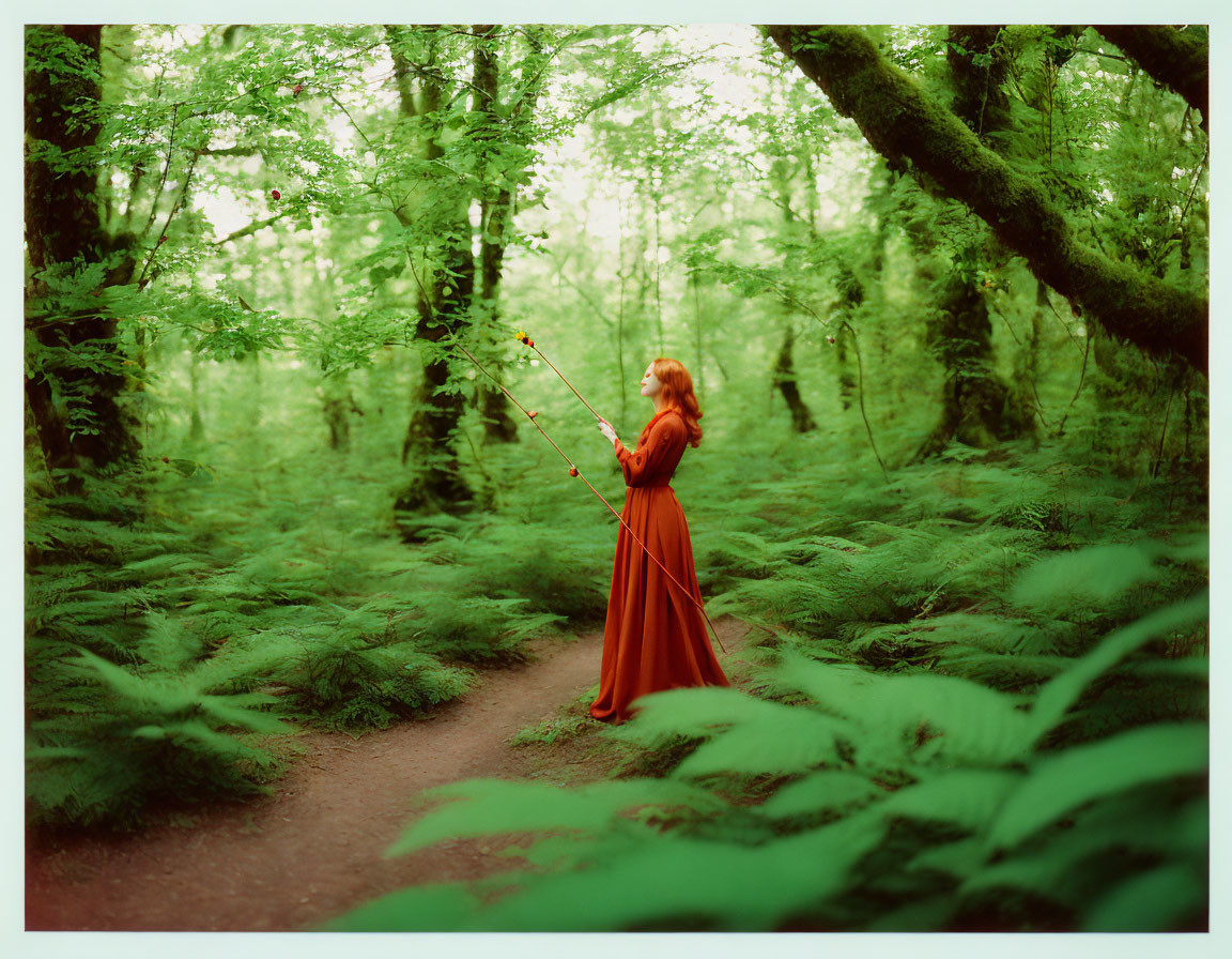 Woman in red dress with bow in lush green forest surrounded by ferns