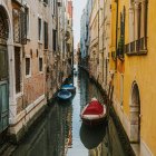 Tranquil canal with old buildings, boats, and reflections