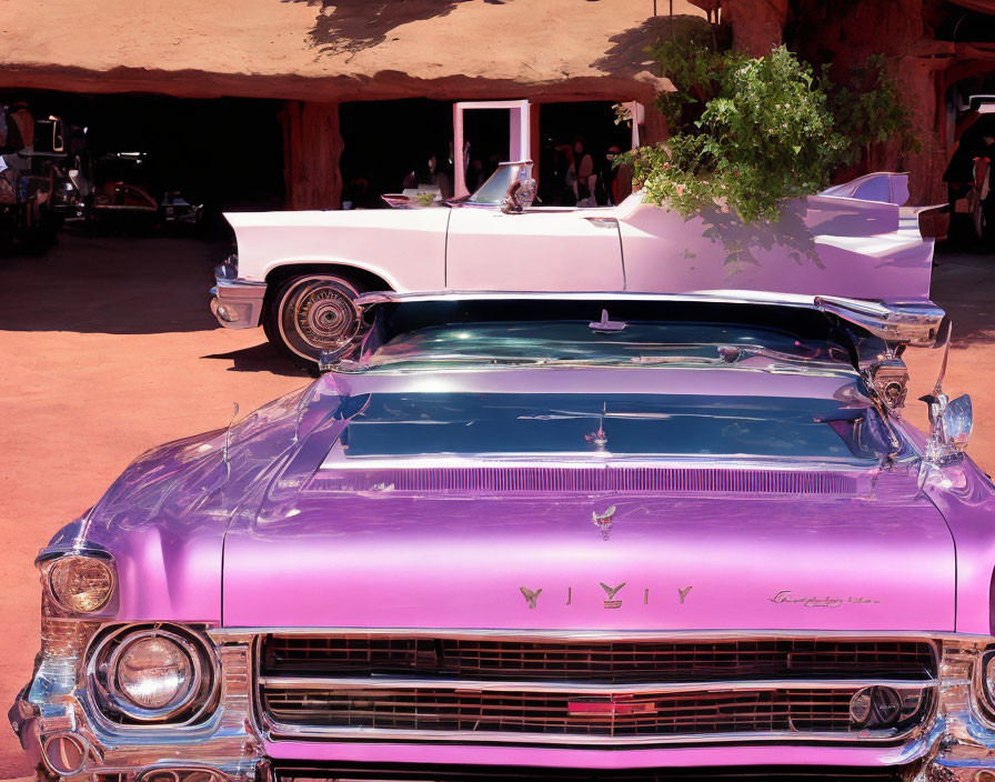 Vintage pink and white cars in desert landscape.
