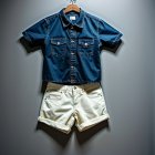 Denim shirt and beige shorts on wooden hanger against gray background