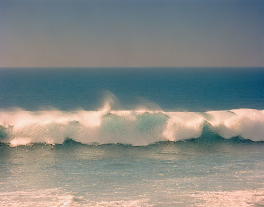 Tranquil ocean wave cresting under gradient sky