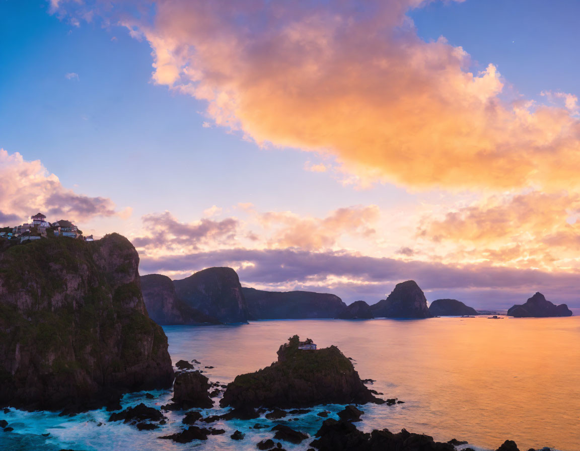 Rocky cliffs and small island at sunset with pastel clouds over calm sea