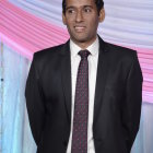 Stylish man in suit and tie with sunglasses and headphones under helicopter in sky