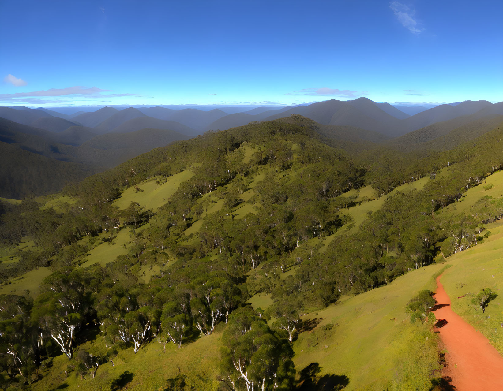 Scenic landscape with green hills, blue sky, and winding dirt road