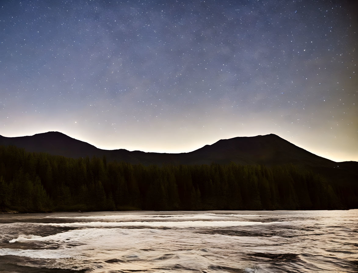 Starry night sky over mountain silhouette and flowing river