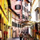 Colorful town street scene with buildings, flowers, and people under a bright blue sky