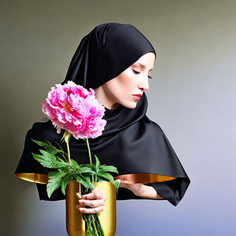 Woman in black hijab with pink flower in gold vase on grey background