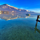 Mountainous landscape with clear lake, steamboat, and sailboat