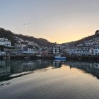 Vintage boats and thatched-roof cottages in tranquil dusk harbor