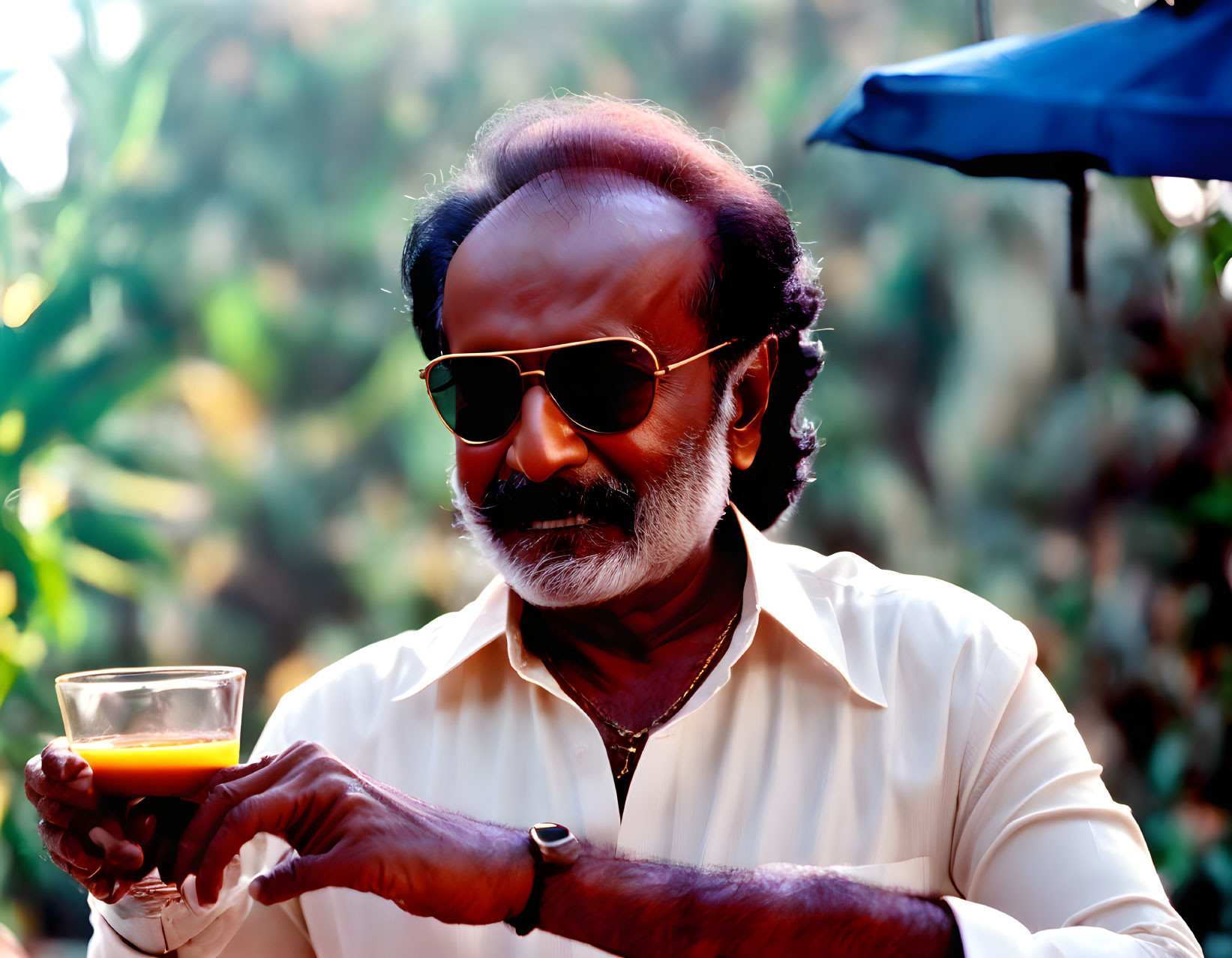 Bearded man with sunglasses holding a cup of tea in warm sunlight