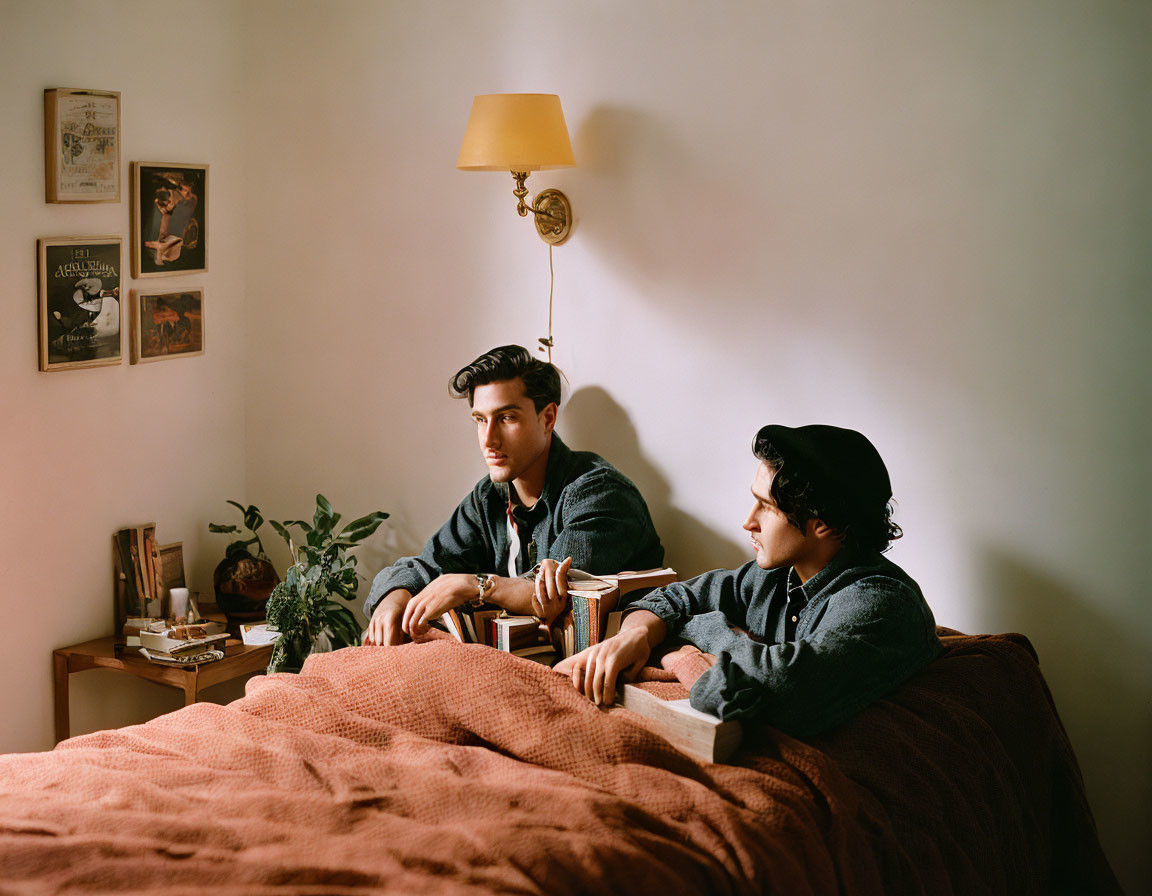 Two People Sitting on Bed in Cozy Room with Wall Lamp and Plants