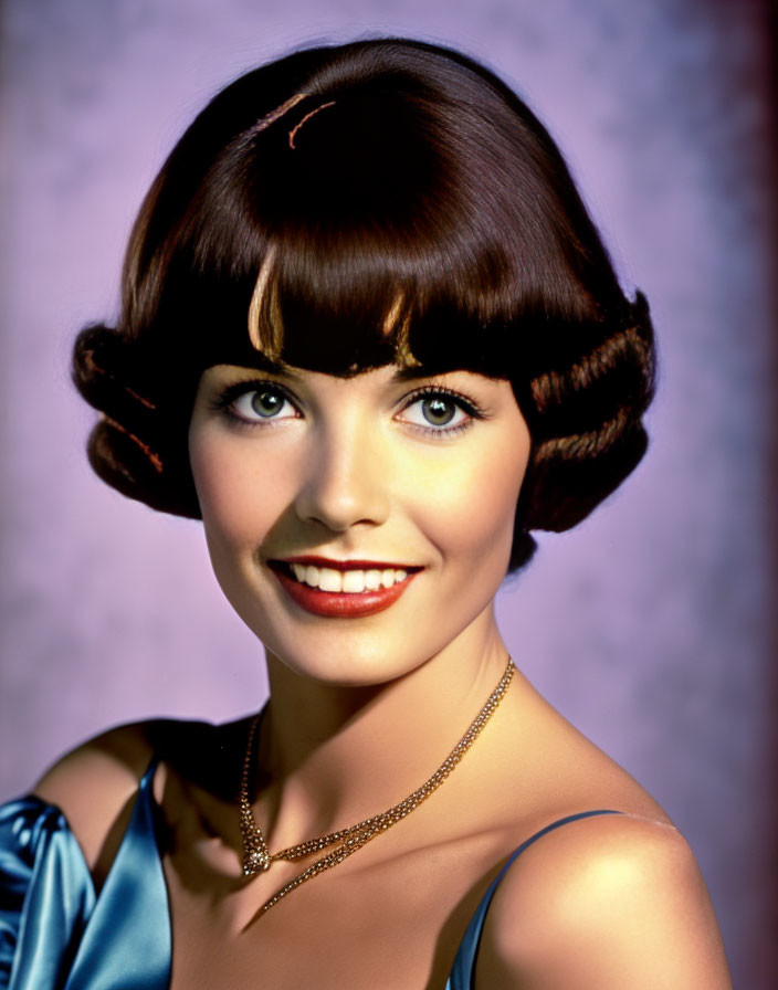 Smiling woman with curly brown hair in blue satin dress on purple backdrop