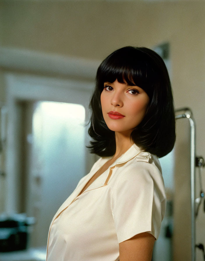 Black-haired woman in white blouse poses indoors.