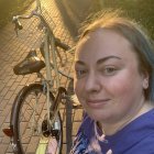 Smiling young woman with blue hair and bicycle in warm sunlight