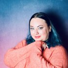 Woman with Blue Hair in Cosmic Setting Hugging Knees in Pink Blanket