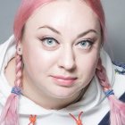 Young woman portrait with pastel hair and feathered garment on soft background