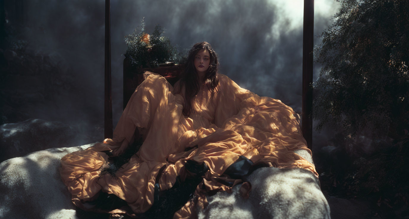 Woman sitting on bed with gold fabric and bouquet in misty atmosphere