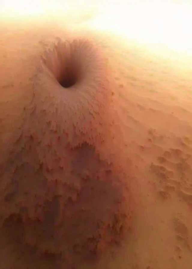 Cone-shaped sand structure with central hole on warm-toned background