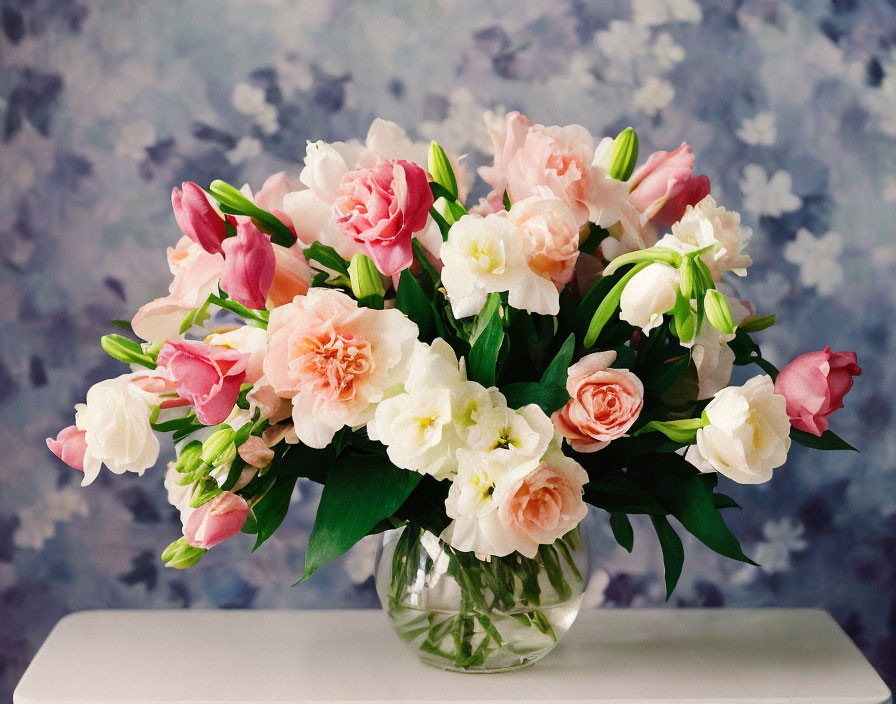 Vibrant pink and white flower bouquet in glass vase with blurred floral background