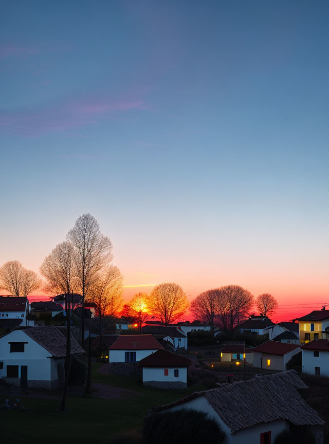 Tranquil neighborhood at sunset with vivid orange hues and silhouetted trees.