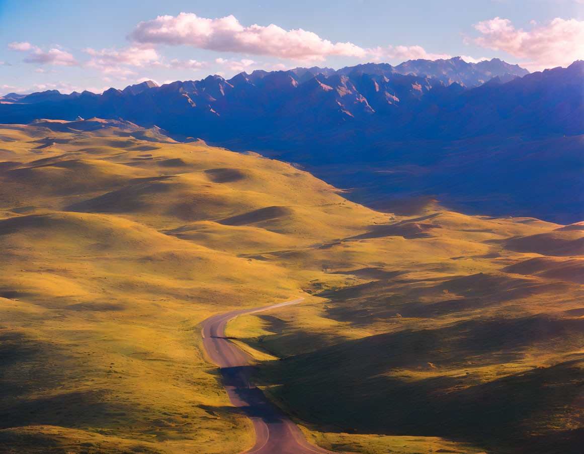 Scenic winding road through green hills and mountains under blue sky