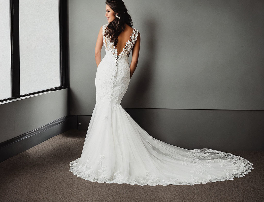 Elegant bride in lace wedding gown by window