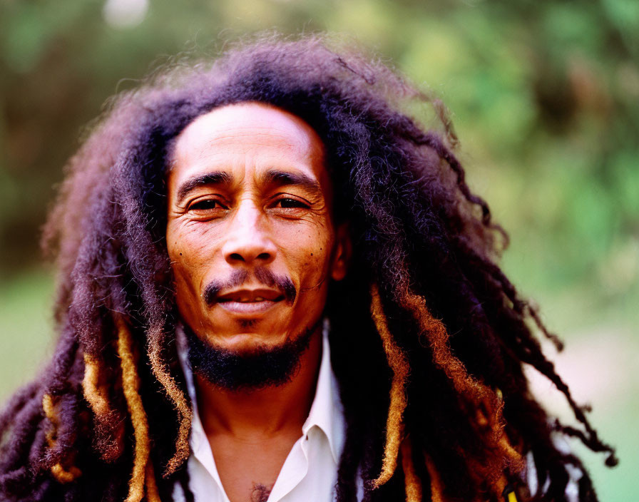 Portrait of Person with Long Dreadlocks in Serene Expression on Blurred Green Background