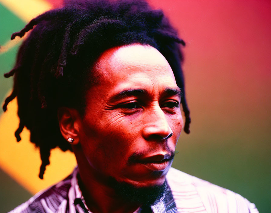 Portrait of a person with dreadlocks in striped shirt against colorful background