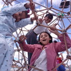 Kids playing on red climbing net under cloudy sky