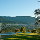 Tranquil landscape with steel truss bridge over river and lush green hills