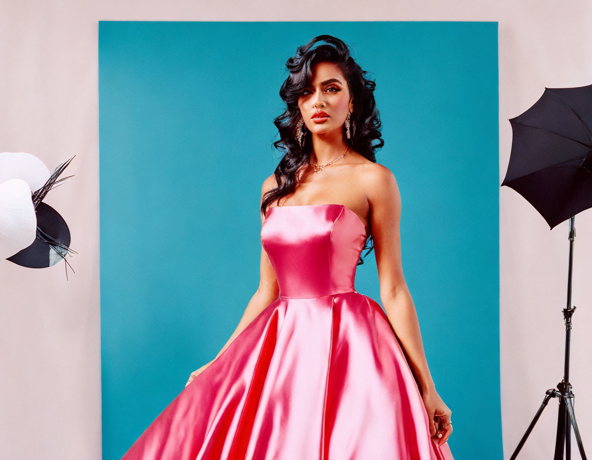 Woman in Pink Strapless Gown Poses in Studio with Blue Background