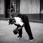 Person in hip-hop attire with basketball in urban setting.