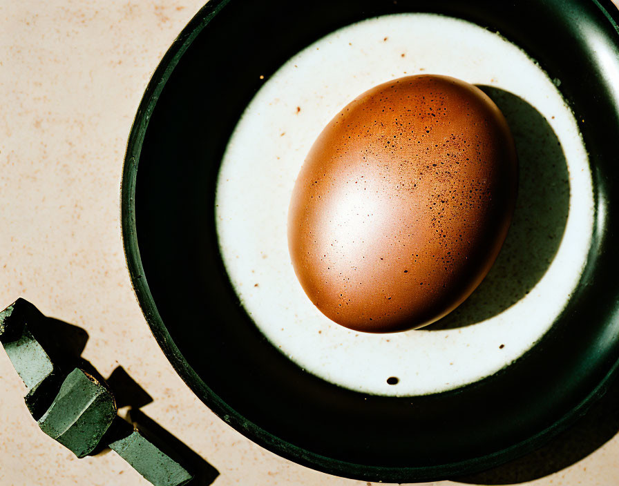 Brown egg in black ceramic-coated frying pan on textured surface