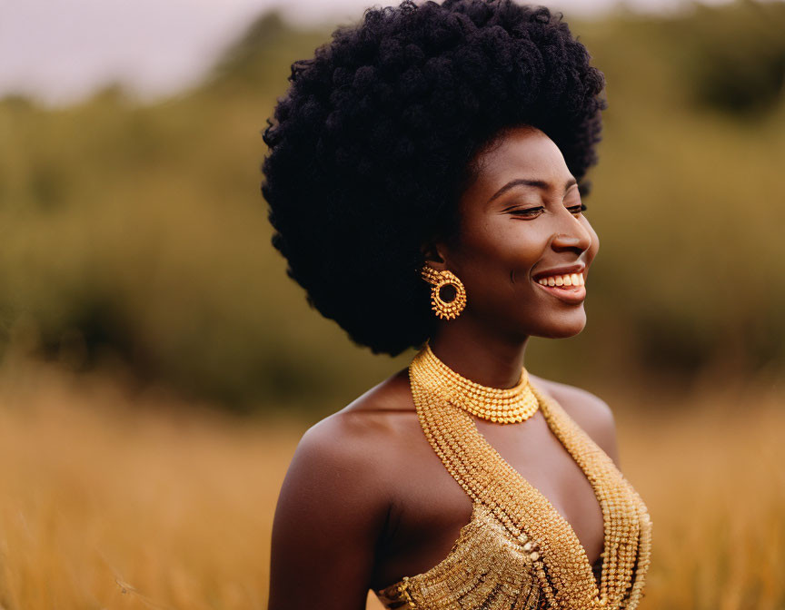 Woman with large afro and gold jewelry in grassy field