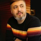 Man with neat hair in striped sweater in contemplative mood against blurred background