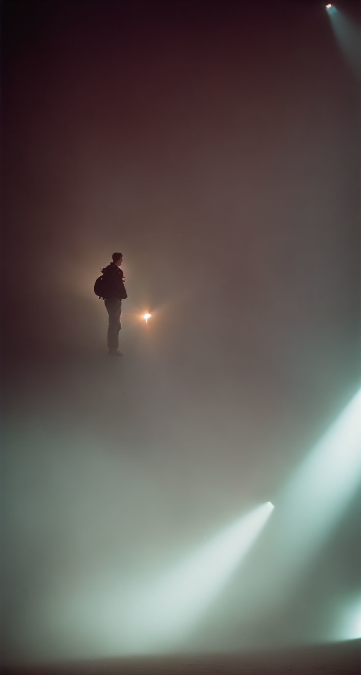 Silhouette of person in misty space with diagonal light beams