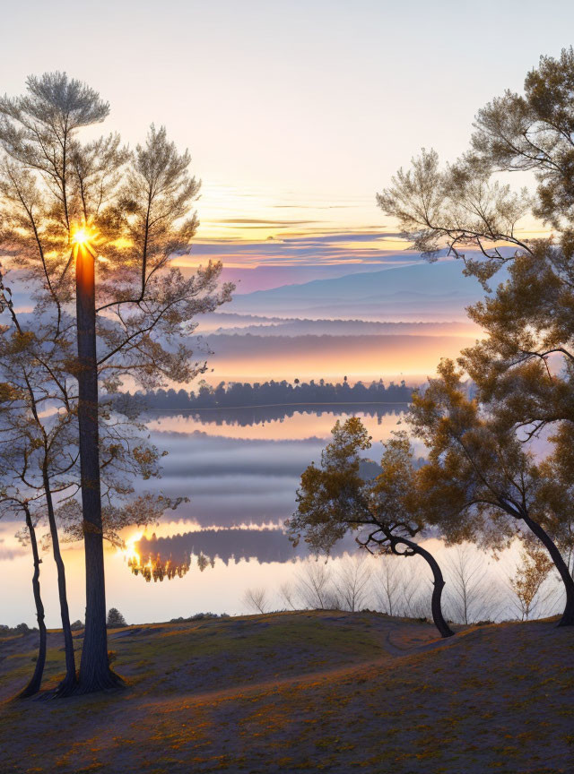 Sunrise scenery: sunburst through trees, misty lake, reflections, layered hills