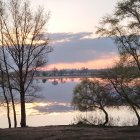 Sunrise scenery: sunburst through trees, misty lake, reflections, layered hills