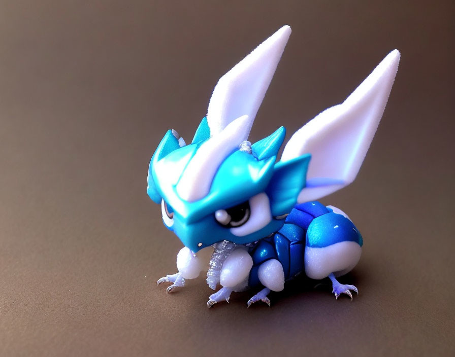 Blue and White Dragon-Like Figurine with Gem-Like Details on Gray Background