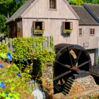 Rustic wooden watermill by tranquil stream surrounded by greenery