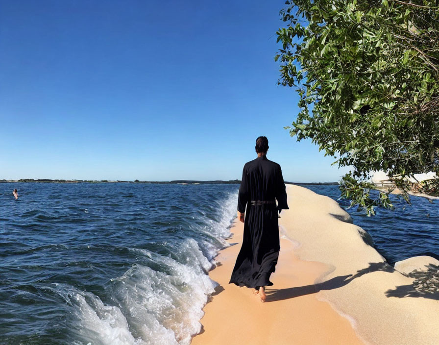 Person in Black Robe Walking on Narrow Sandbank Between Blue Waters