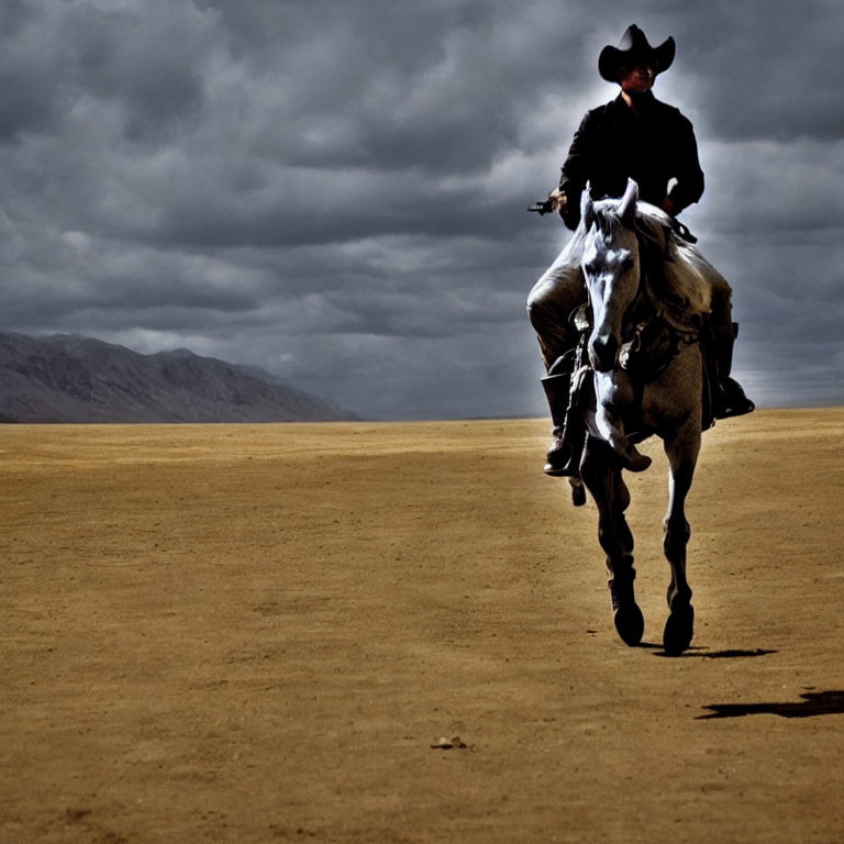 Lone cowboy on white horse in desolate landscape under overcast skies